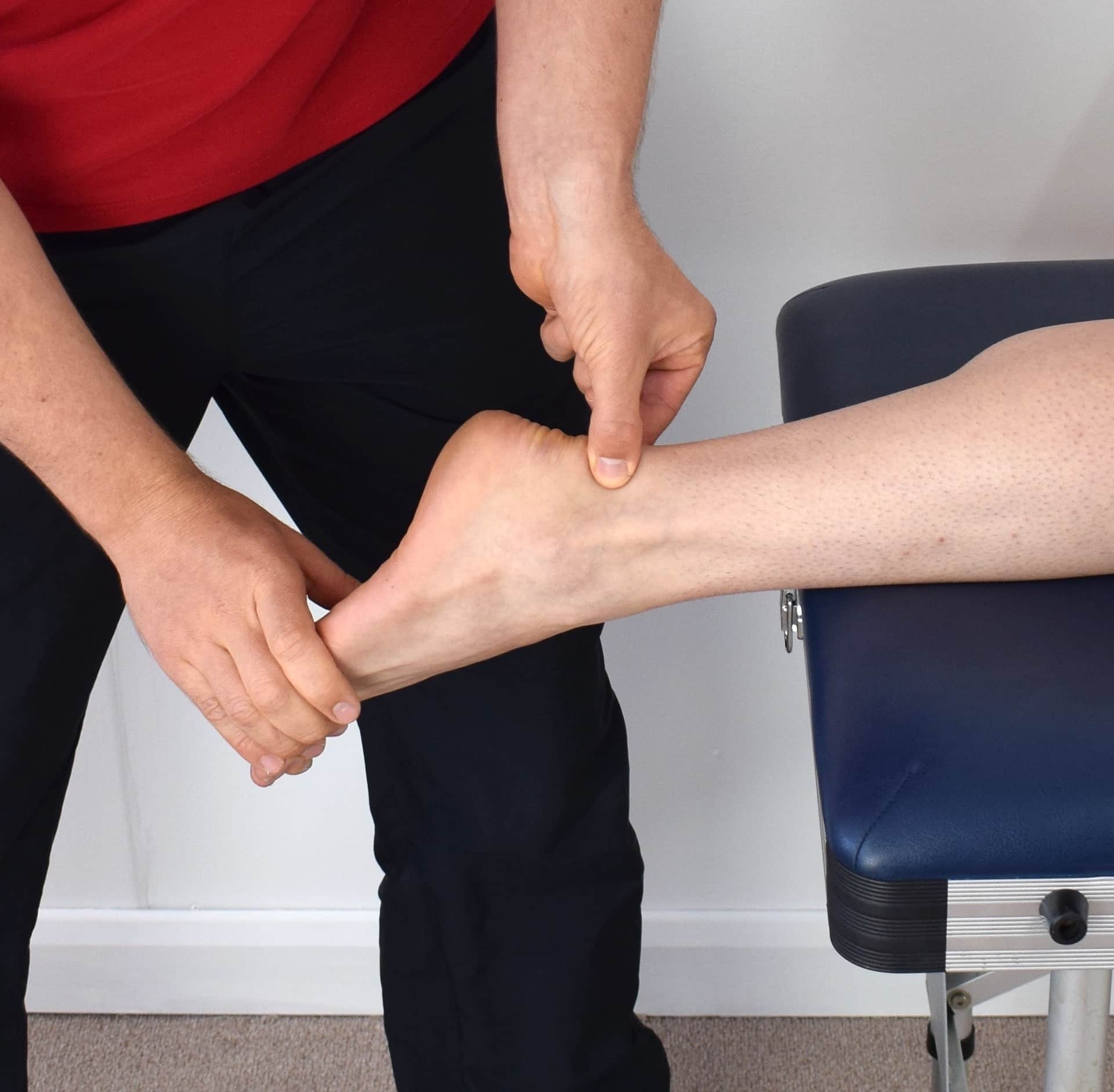 Therapist treating a patient with an ankle sprain. Seeking professional help is one of the key steps to coping with injury recovery setbacks.